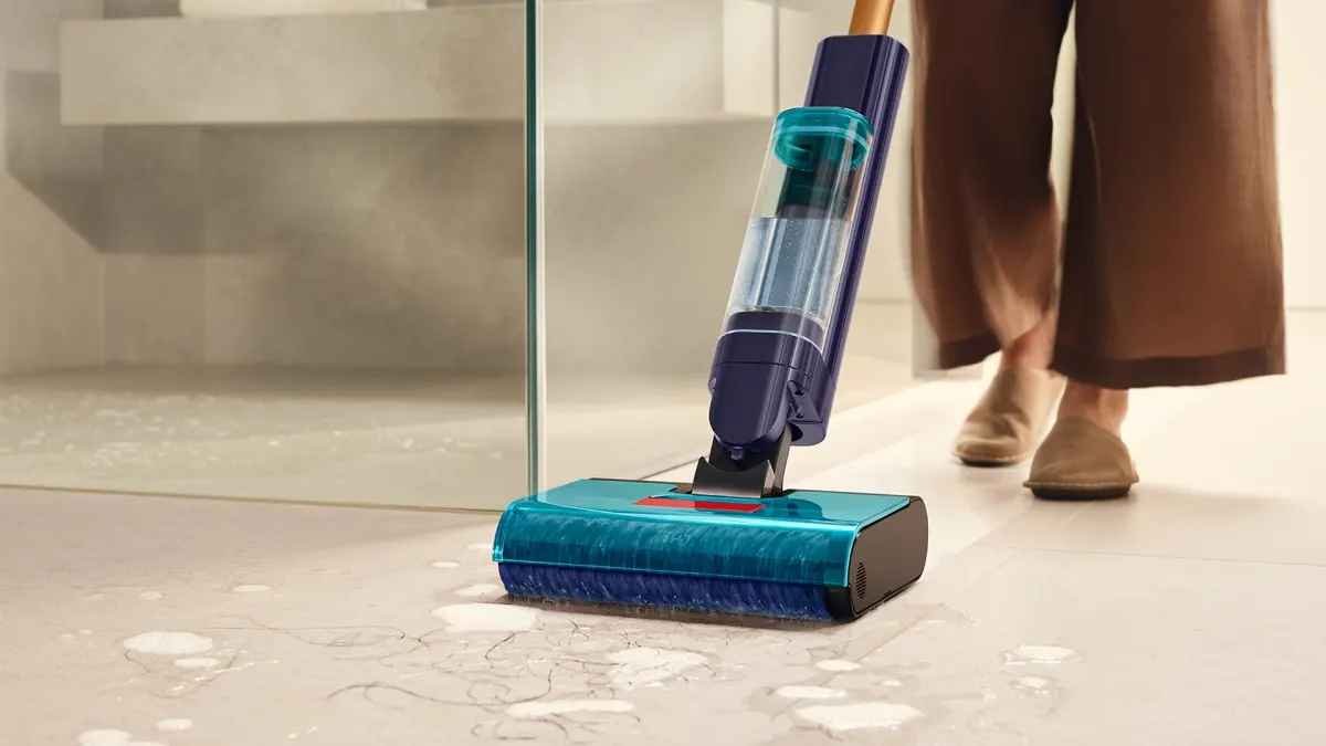 Eine Person saugt nasse Badezimmerfliesen mit dem Nass- und Trockensauger Dyson Clean+Wash Hygiene.