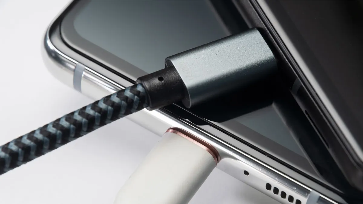 Zwei Smartphones mit eingesteckten Ladekabeln liegen übereinander gestapelt.