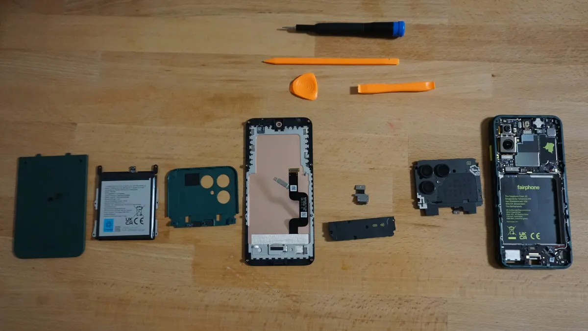 Die Einzelteile eines zerlegten Fairphone 6 und verschiedene Werkzeuge.