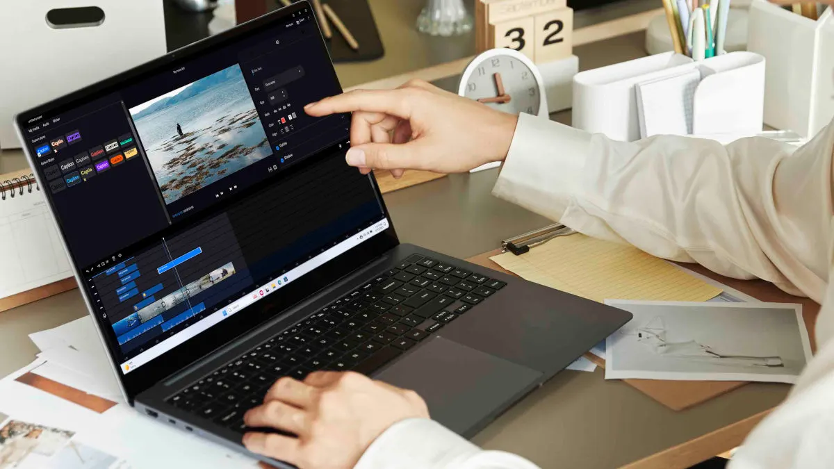 Eine Person bearbeitet ein Video auf einem Laptop. Der Laptop zeigt eine Bearbeitungssoftware mit Zeitleiste und Vorschaufenster. Ein Kalender und Stifte sind im Hintergrund.