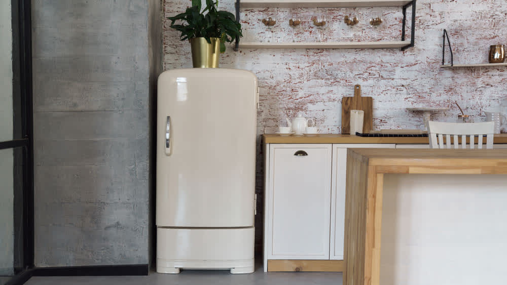 Cremefarbener Retro-Kühlschrank in rustikaler Küche in Naturtönen