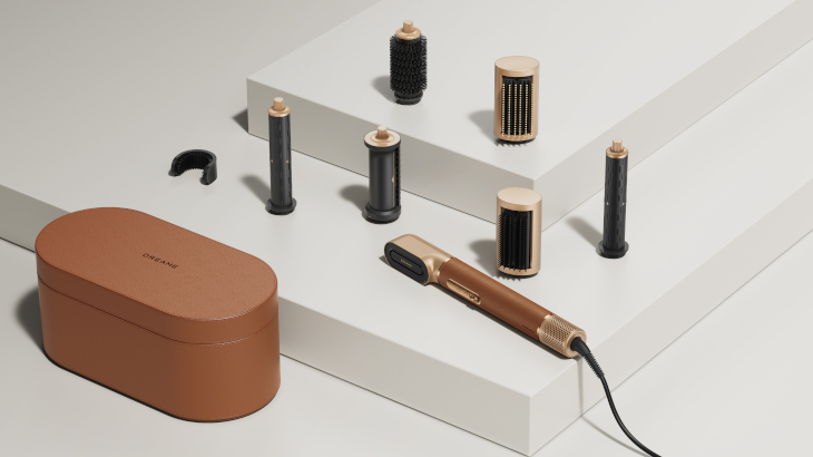 Ein braunes Etui, ein schwarzer Clip und ein Haarstylinggerät mit Aufsätzen liegen auf weißem Untergrund.