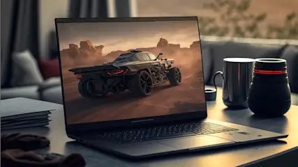 Ein Laptop zeigt ein Auto in einer Wüstenlandschaft. Tasse, Lautsprecher und Bücher liegen auf einem Tisch vor einer Couch.
