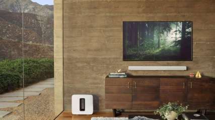 Sonos-Soundbar Arc unter einem TV in einem Wohnzimmer, daneben Sonos Sub.