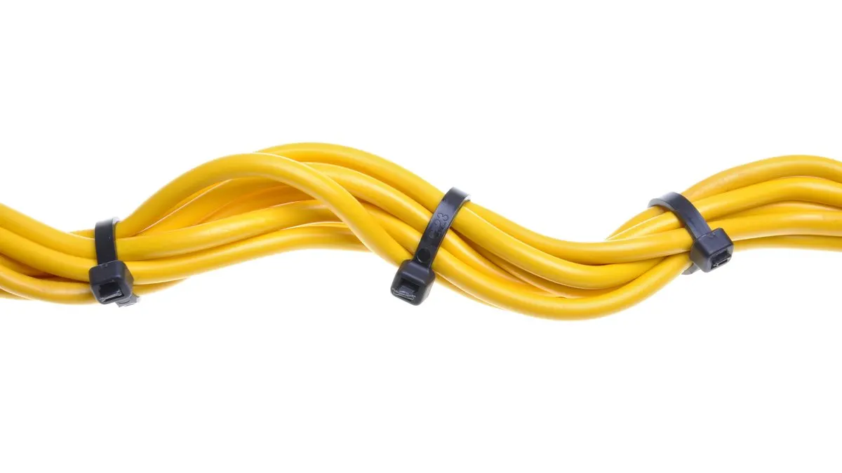 Gelbe Kabel sind mit schwarzen Kabelbindern auf einem weißen Hintergrund befestigt.