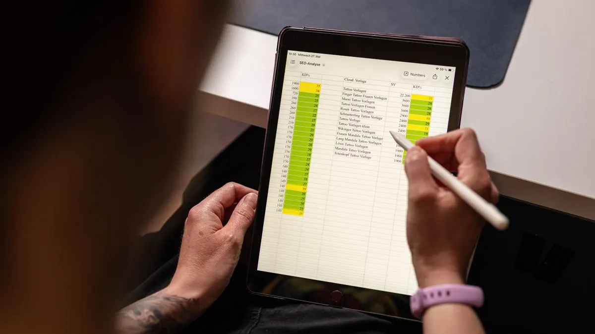 Ein iPad mit einer Excel-Tabelle und darüber eine Hand, die einen Apple Pencil hält.