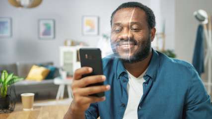 Mann scannt sein Gesicht mit seinem Smartphone.