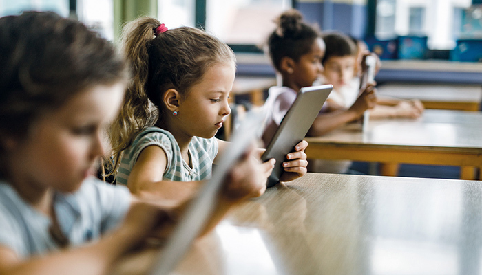 Kinder im Klassenzimmer nutzen Tablets; Gesichter verpixelt, Fokus auf digitale Bildung. 