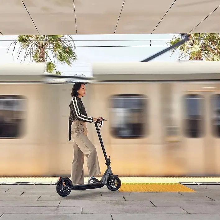 NIU KQi Air E-Scooter neben Straßenbahn im Einsatz.