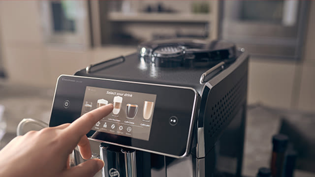 Ein Finger drückt auf den Touchscreen eines Kaffeevollautomaten.