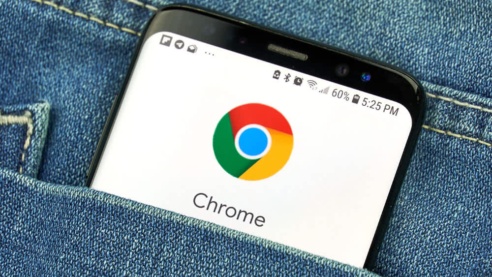 Ein Smartphone mit dem Logo von Google Chrome auf dem Display steckt in einer Hosentasche.