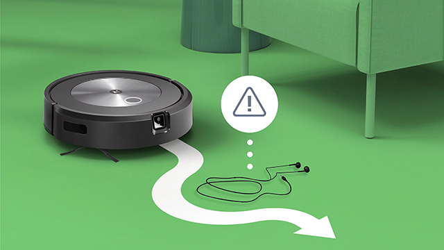 Ein runder, schwarzer Staubsaugerroboter auf grünem Untergrund mit einem Warnsymbol und Kopfhörern.