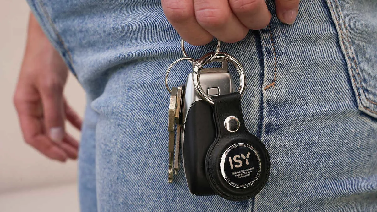 Eine Person hält einen Schlüsselbund mit Auto-, Haus- und ISY-Schlüsselanhänger an einer Jeanshose.