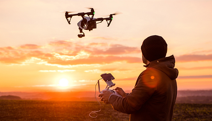 Während eines Sonnenaufgangs lässt ein Mann eine Drohne aufsteigen.