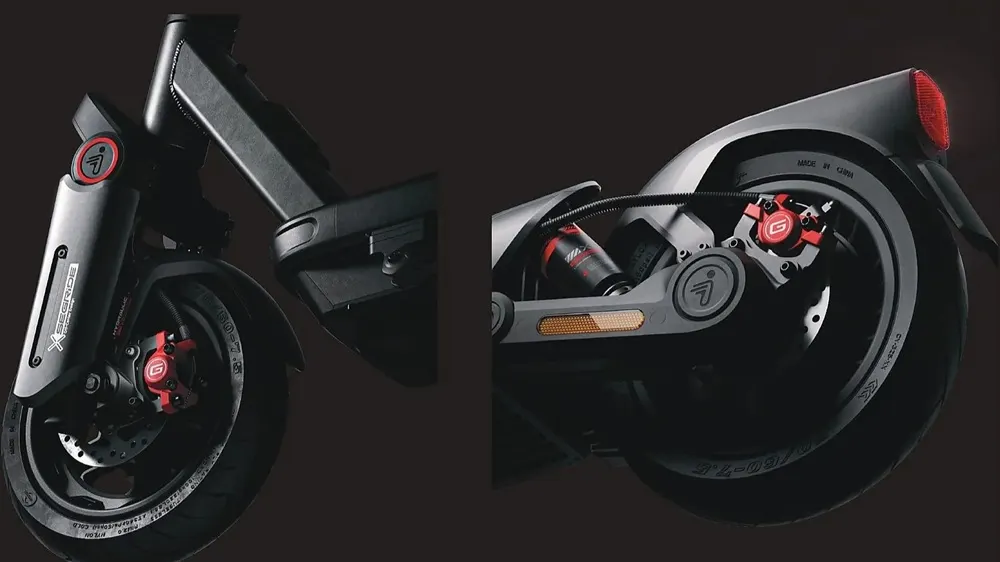 Detailaufnahme SEGWAY Ninebot MAX G3 D E-Scooter: Vorder- und Hinterrad mit breiten Reifen, kräftigen Federungen und roten Scheibenbremsen auf dunklem Hintergrund.