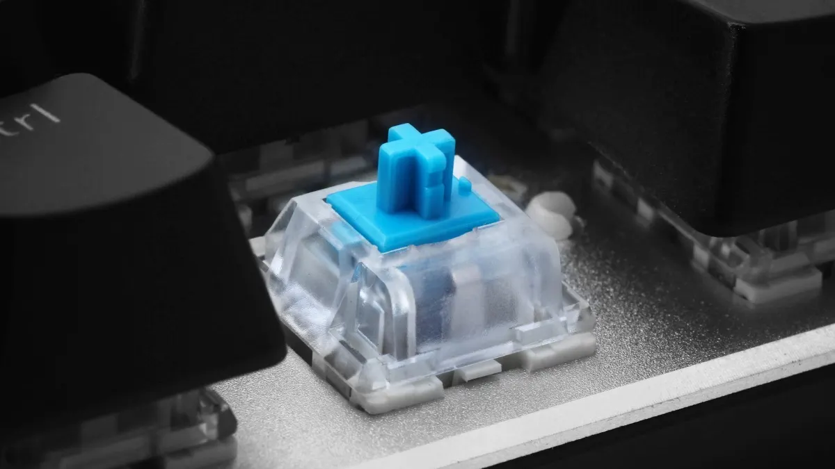 Ein blauer Schalter auf einer mechanischen Tastatur. Er sitzt auf einer Feder in einer transparenten Kunststoffhülle.