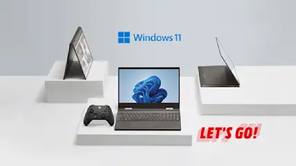 Drei Laptops, ein Xbox-Controller und der Windows 11 Schriftzug auf weißen Podesten vor einem grauen Hintergrund. Roter Text: "LET'S GO!".