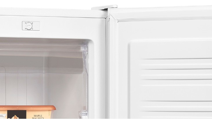 Ein offener, weißer Kühlschrank mit einem Drehknopf zur Temperaturregelung und einer Schachtel mit der Aufschrift "Maple Walnuts".