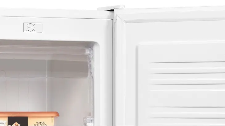 Ein offener, weißer Kühlschrank mit einem Drehknopf zur Temperaturregelung und einer Schachtel mit der Aufschrift "Maple Walnuts".