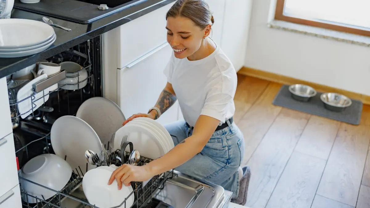 Eine Frau nimmt Geschirr aus einem Geschirrspüler.