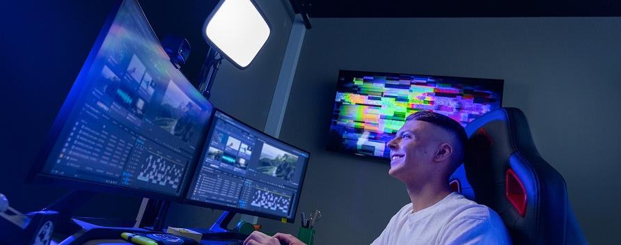 Gamer sitzt im abgedunkelten Raum mit RGB-Licht vor einem beeindruckenden Curved-Gaming-Display