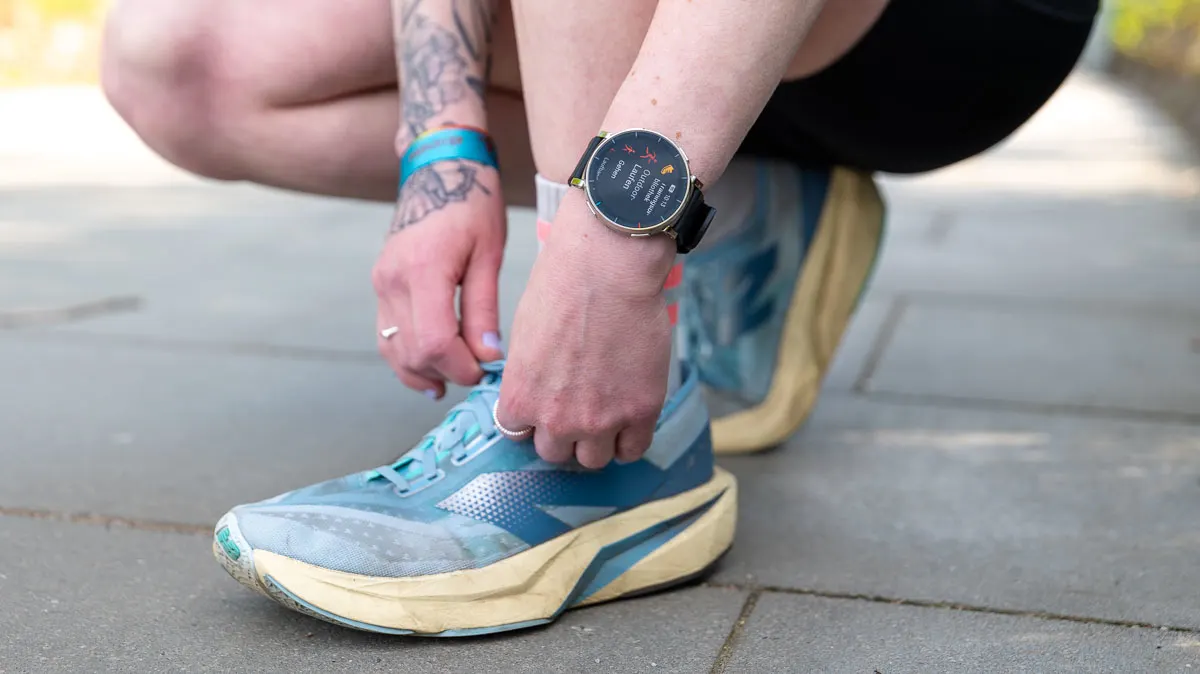 Franzi trägt die Amazfit Active 3 Premium am Arm und bindet sich draußen die Laufschuhe zu.