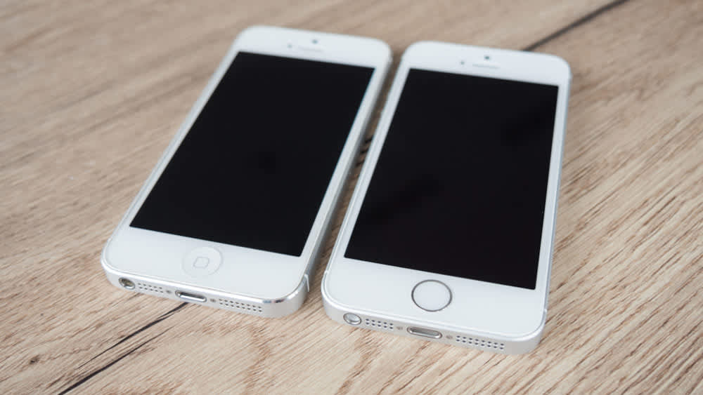 Ein iPhone SE und ein iPhone 5 liegen nebeneinander auf einem Holztisch.
