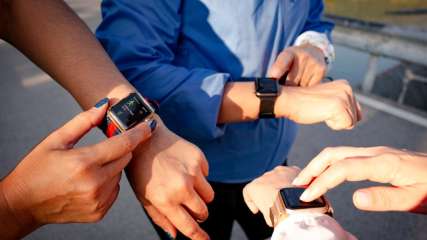 Drei Personen zeigen ihre Smartwatch am Handgelenk und tippen auf die Displays der Uhren.