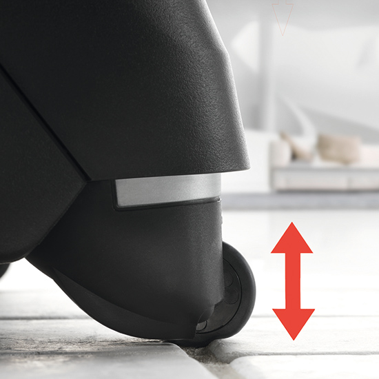 Nahaufnahme eines schwarzen Objekts mit einem Rad auf einem gefliesten Boden und einem roten Pfeil.