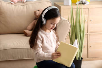 Ein Mädchen mit Kopfhörern liest ein Buch