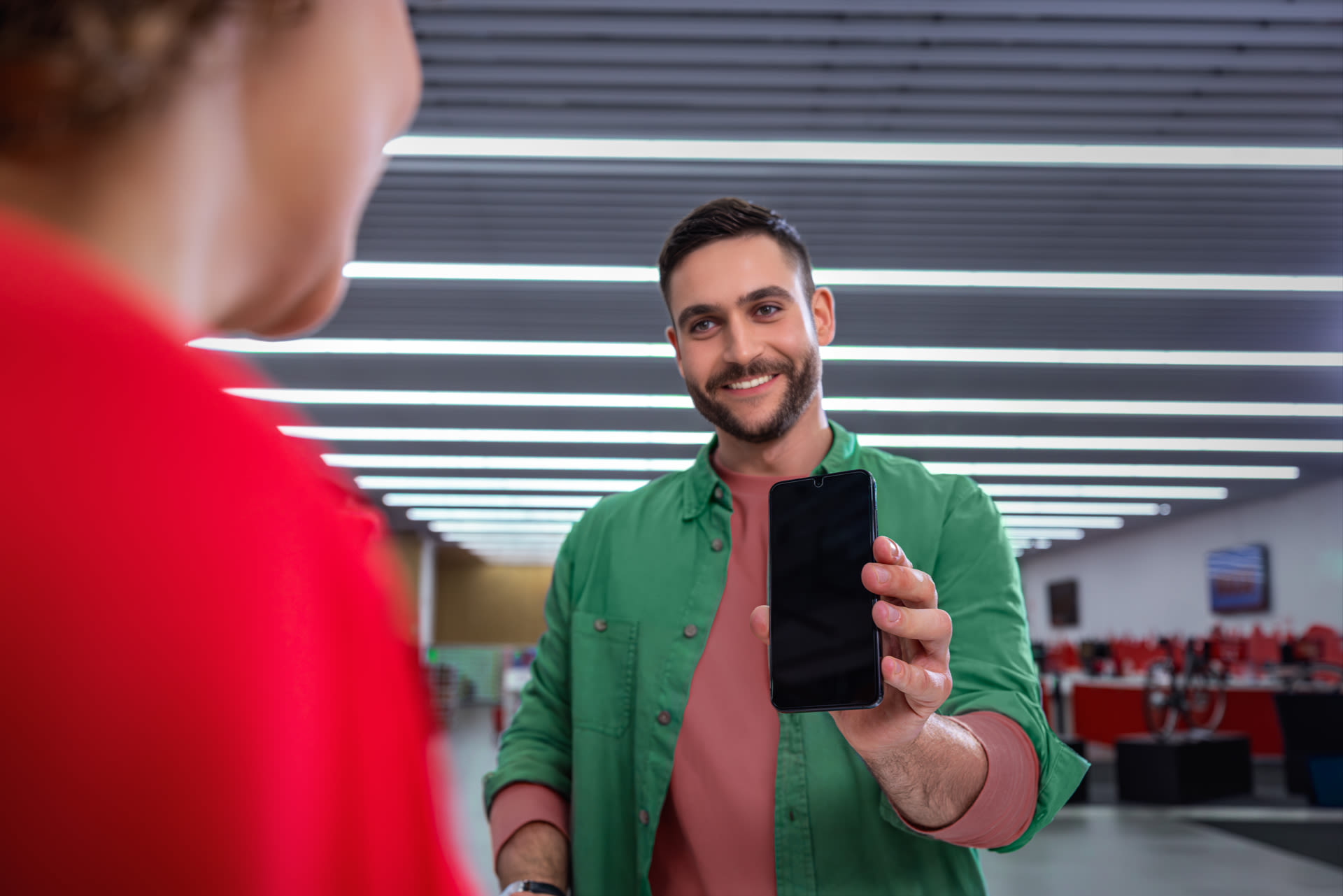 Ein Mann möchte einen Displayschutz auf sein Smartphone auftragen lassen.