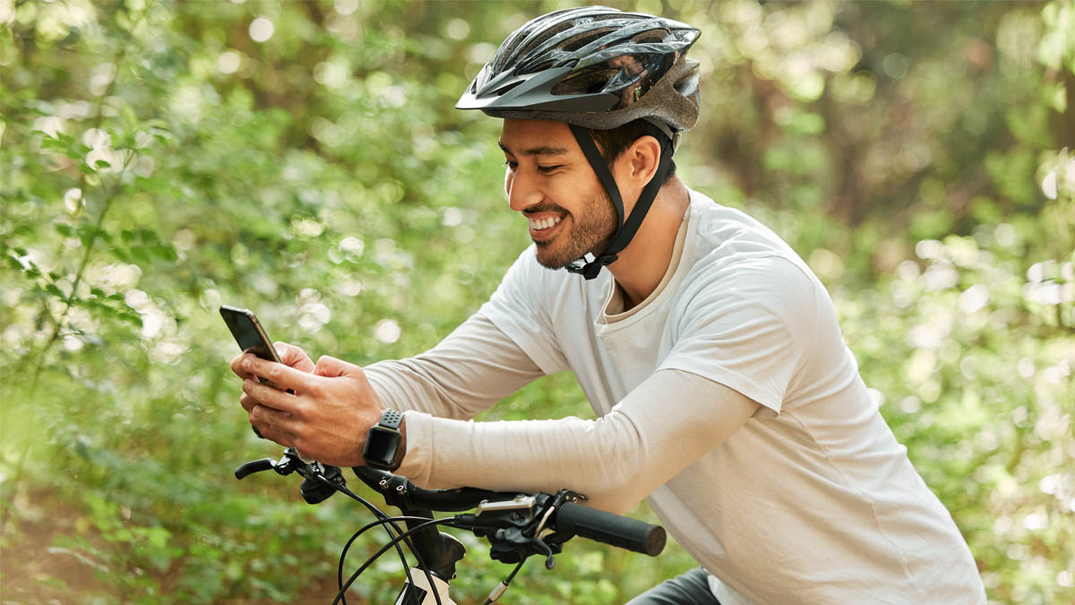 Ein Radfahrer mit blauem Smartwatch-Armband hält einen schwarzen Fahrradlenker mit hellblauen Handschuhen.