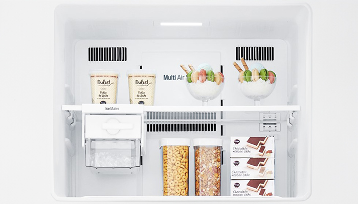 Ein weißer Kühlschrank mit Regalen enthält Joghurt, Müsli in Behältern und Schokoladenkuchen in Schachteln.