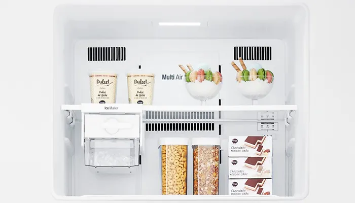 Ein weißer Kühlschrank mit Regalen enthält Joghurt, Müsli in Behältern und Schokoladenkuchen in Schachteln.