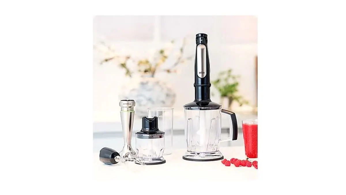 Set mit Braun Stabmixer, Mixaufsätzen, Messbecher und Zerkleinerer auf einer Küchenarbeitsplatte, daneben ein Glas roter Smoothie.