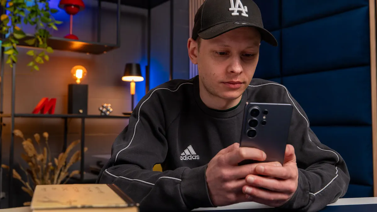 Alex sitzt an einem Tisch und tippt etwas auf dem Samsung Galaxy S26 Ultra.