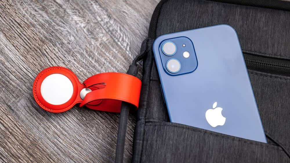 Ein roter AirTag ist an einer Tasche befestigt in der ein iPhone liegt.