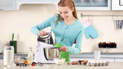 Eine Frau steht in einer Küche und benutzt eine Küchenmaschine.