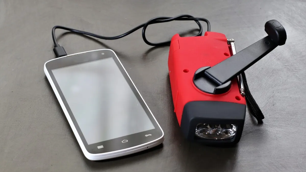 Ein Smartphone ist per Kabel an ein Kurbelradio angeschlossen.
