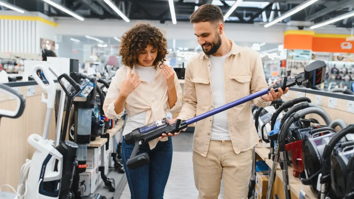 Eine Frau und ein Mann begutachten einen Akku-Staubsauger im Fachhandel.