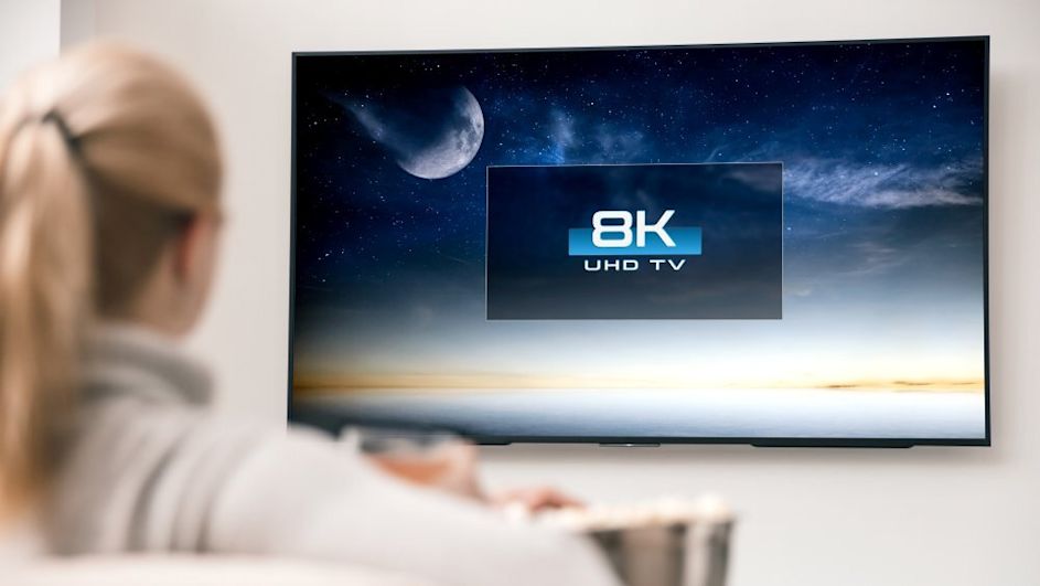Frau schaut auf 8K TV Fernseher
