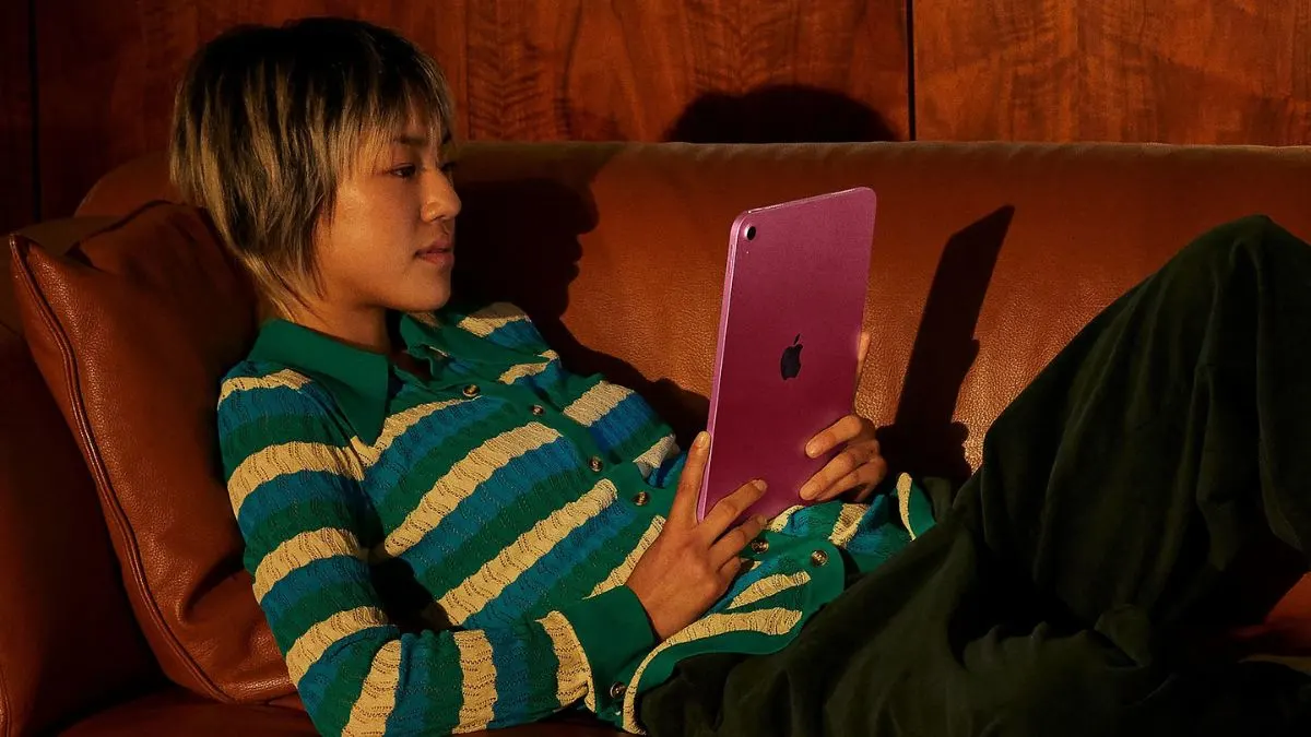 Eine Frau liegt auf einem Sofa und schaut auf das Tablet Apple iPad 11.