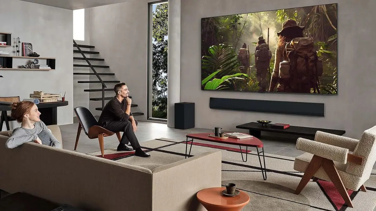 Eine Frau und ein Mann sehen einen Film auf dem an der Wand befestigten Fernseher LG G5.