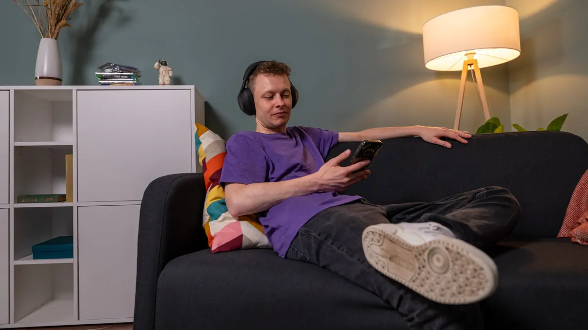 Alex sitzt auf einem Sofa und testet den Sound des Kopfhörers Sony WH-1000XM6.