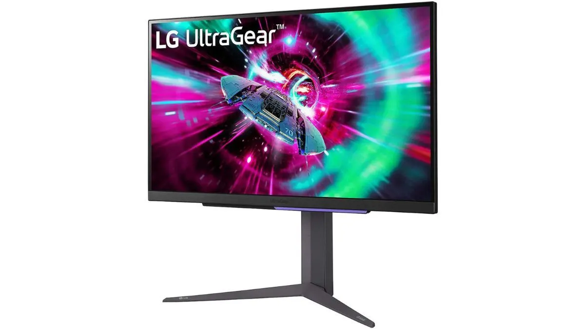 Ein schwarzer LG UltraGear Monitor steht auf einem grauen Ständer. Der Bildschirm zeigt ein Raumschiff vor einem Hintergrund aus grünen und pinkfarbenen Lichtstrahlen.
