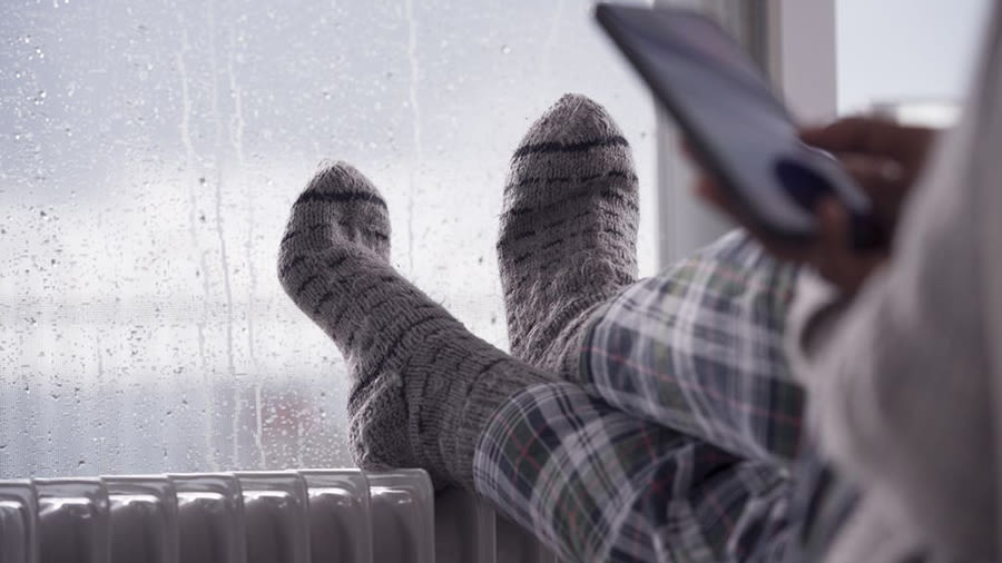 Füße mit dicken Socken auf einer Heizung am Fenster