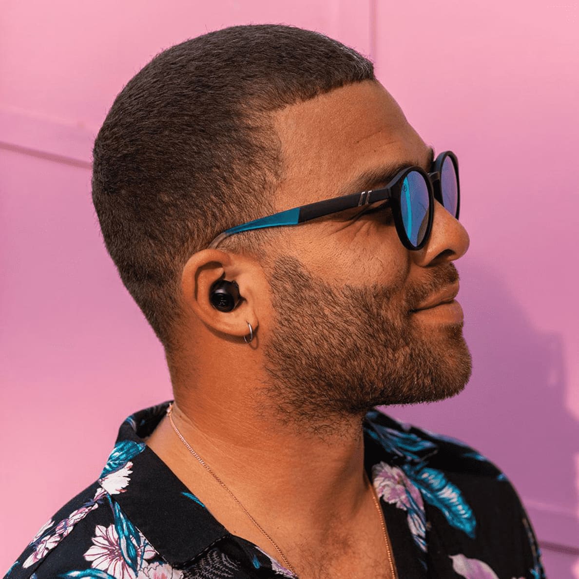 Man mit kurzem Haarschnitt und Sonnenbrille schaut nach rechts und trägt schwarze JLAB Go Air Pop