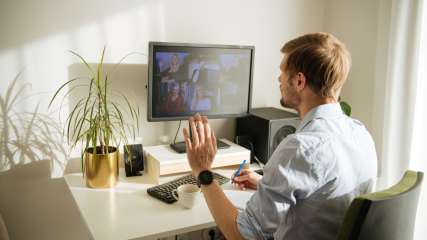 Ein Mann ist im Home-Office in einem virtuellen Meeting.