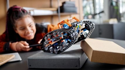 Ein Mädchen spielt mit einem Lego Roboter