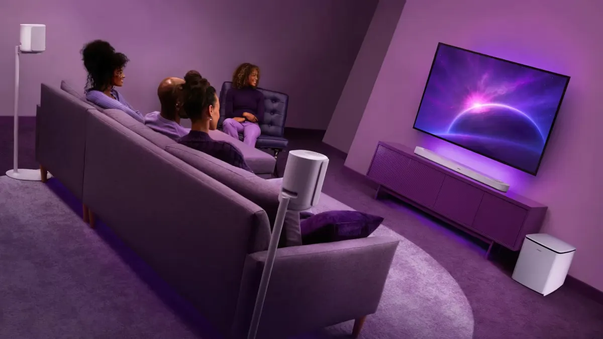 Eine Gruppe von Personen schaut in einem Wohnzimmer einen Film an. Im Wohnzimmer stehen verschiedene Produkte aus der Bose Lifestyle-Ultra-Serie.